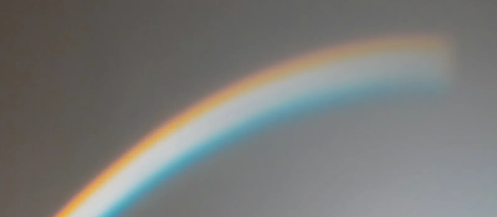 Un arc-en-ciel de lumière dessiné sur un mur gris