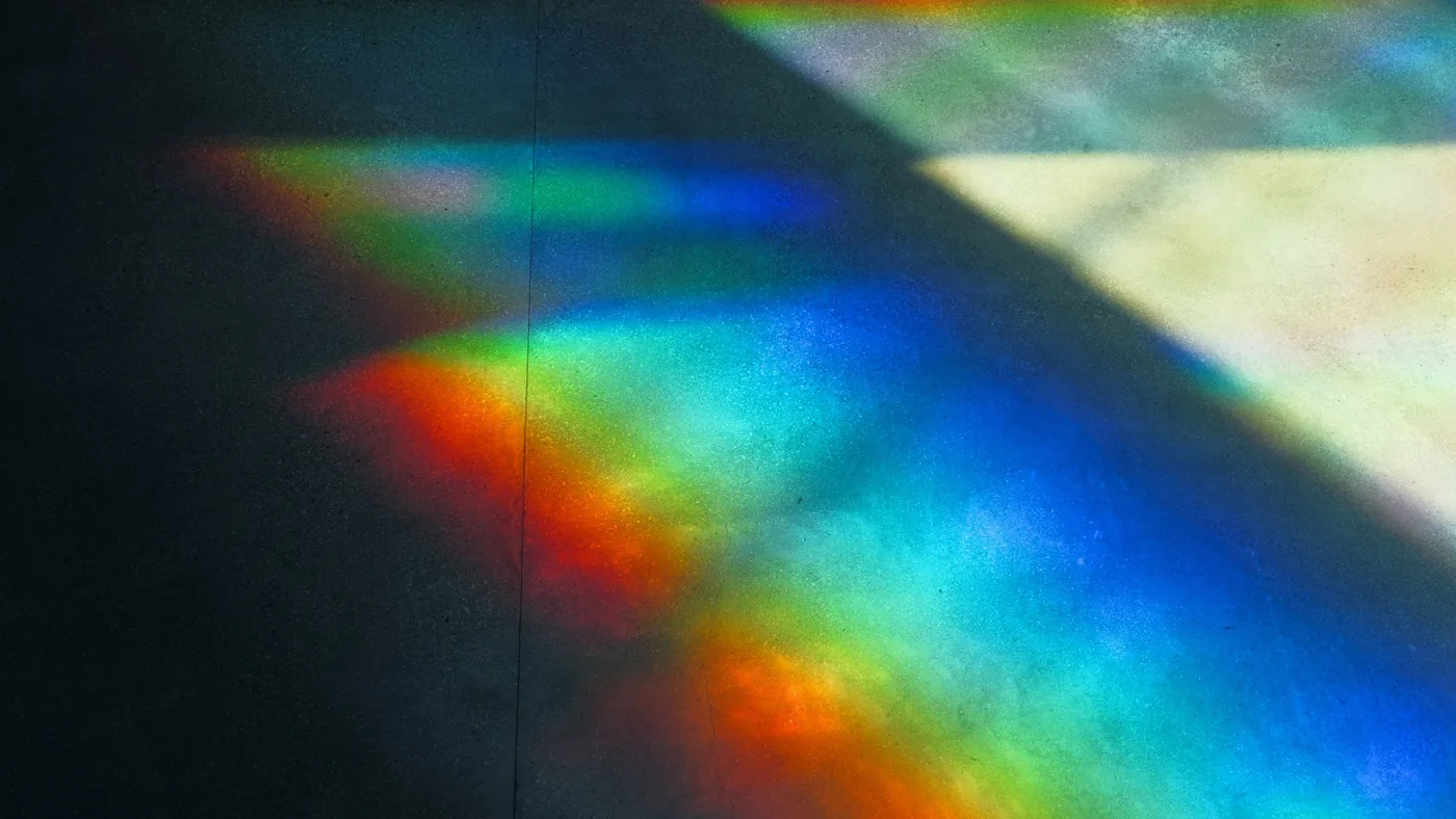 Des éclats de lumière aux couleurs de l'arc-en-ciel sur un mur sombre
