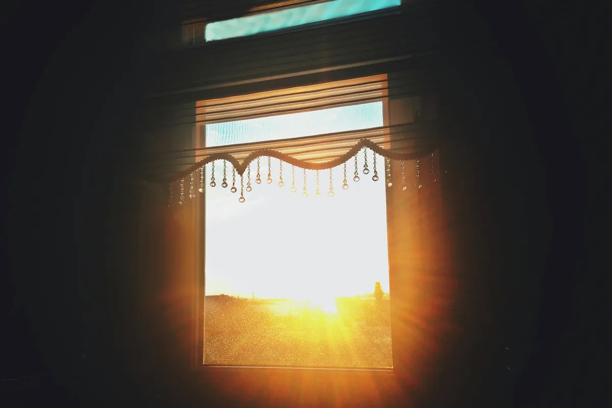 Le soleil couchant derrière une fenêtre aux persiennes entrouvertes