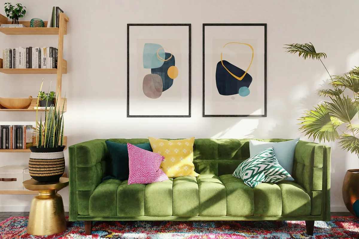 Un salon clair avec un canapé vert, des coussins colorés et des cadres au mur